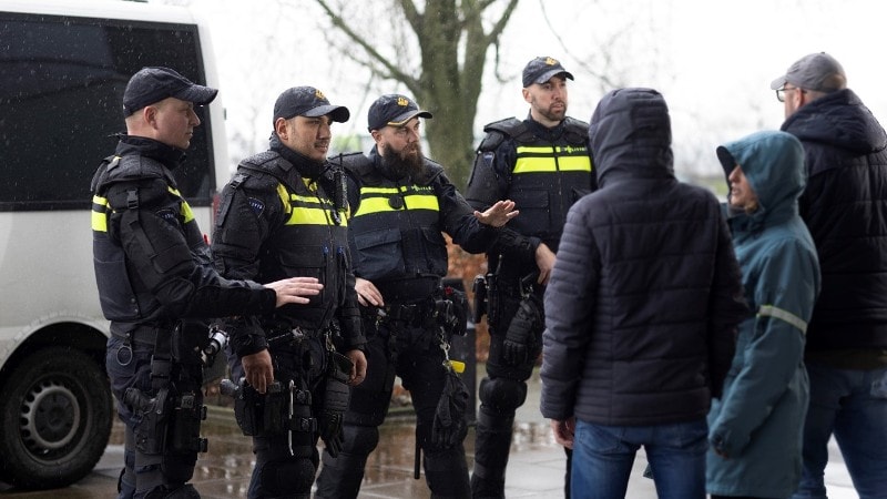 Politiemedewerkers in ME-uniform in gesprek met burgers.