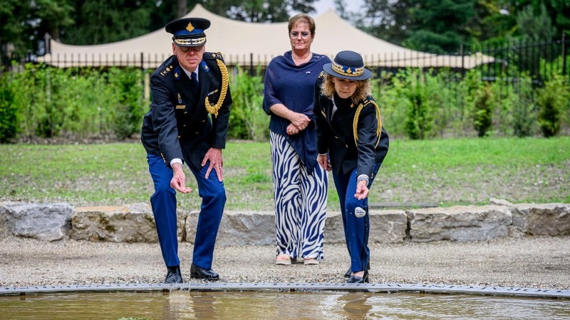 Korpschef Janny Knol (rechts) en Leonard Kok, directeur van de Politieacademie, werpen een kiezelsteen in De Spiegelvijver.